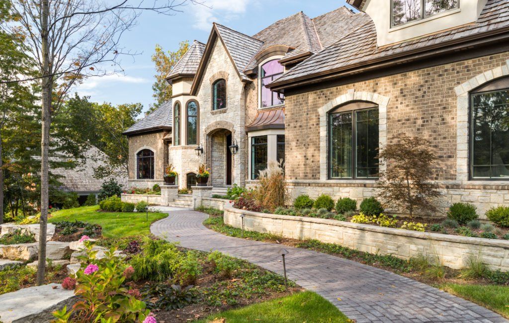 A large stone house with a lush green lawn and a walkway leading to it.