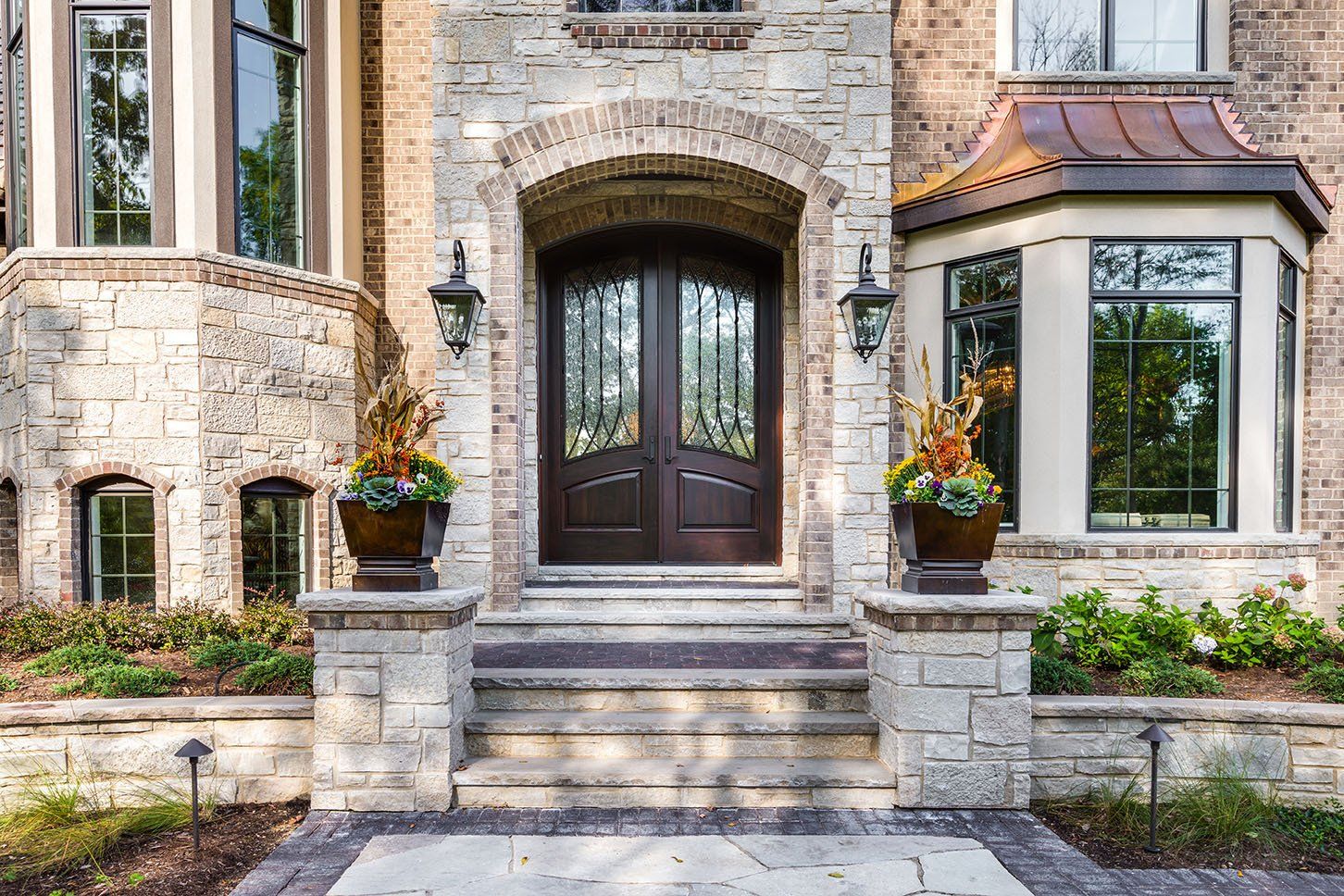 The front door of a large brick house with a wooden door and a copper roof.