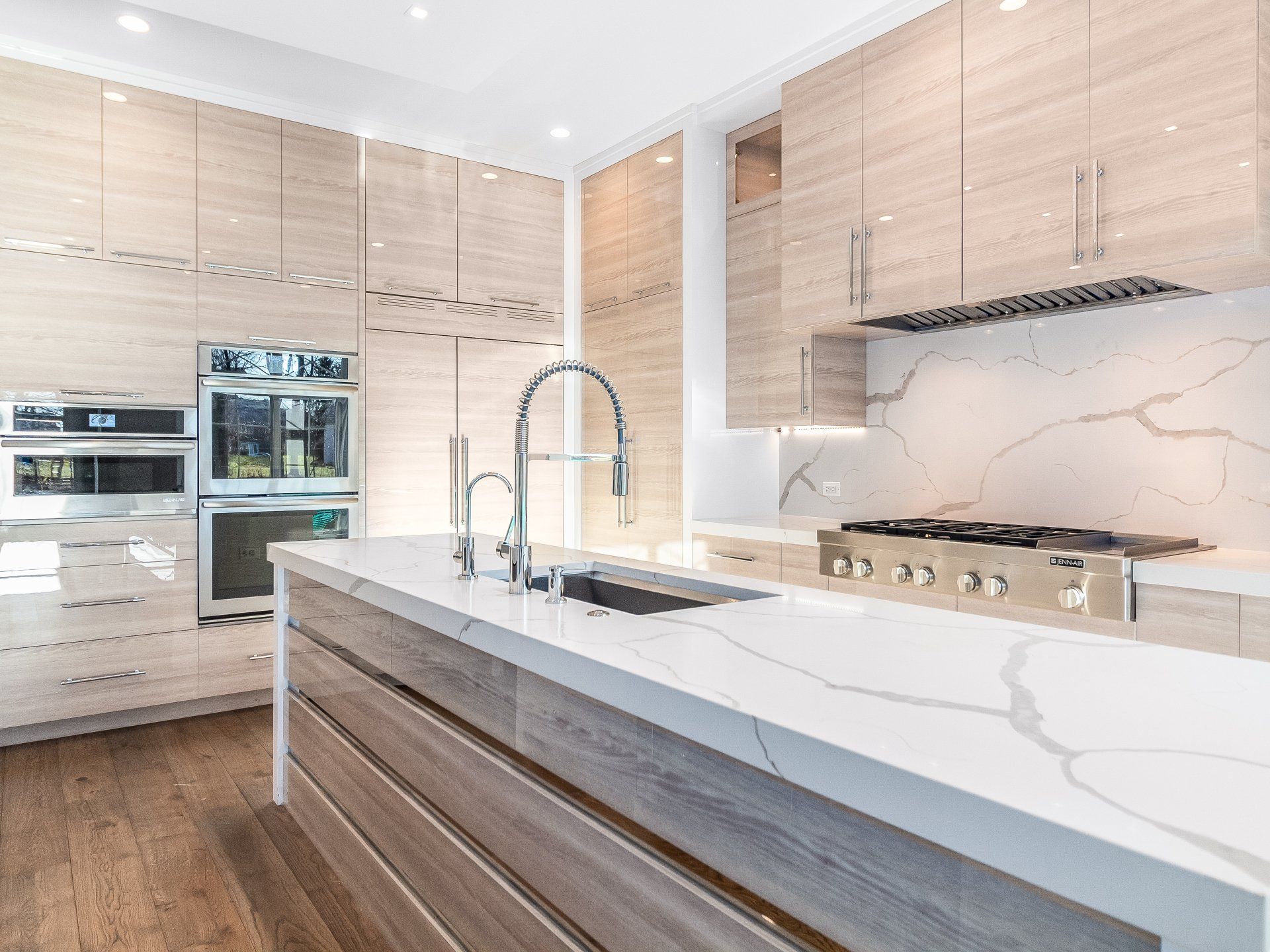 A kitchen with wooden cabinets , white counter tops , a sink and a stove.