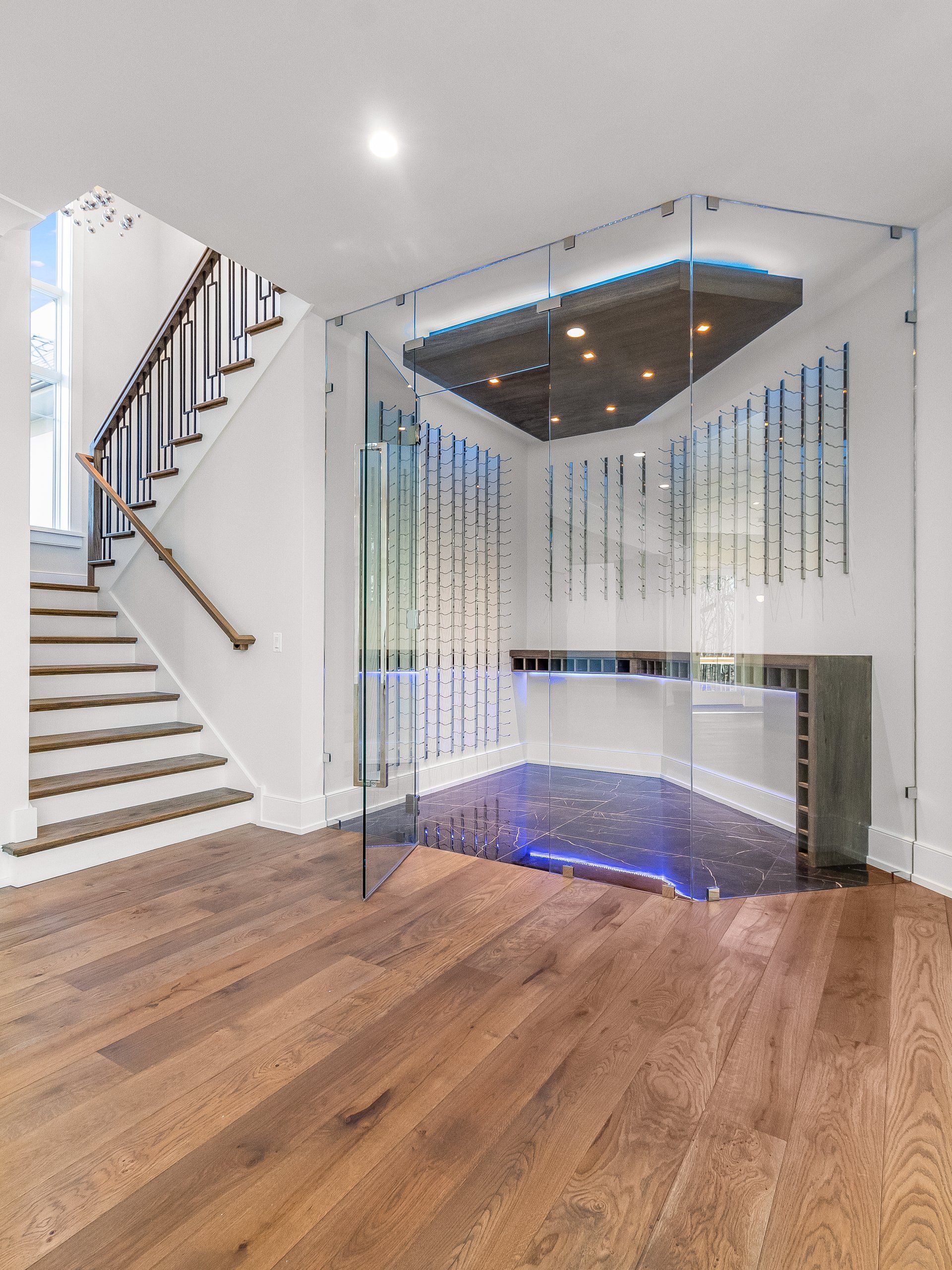 There is a staircase in the background and a glass wall in the middle of the room.