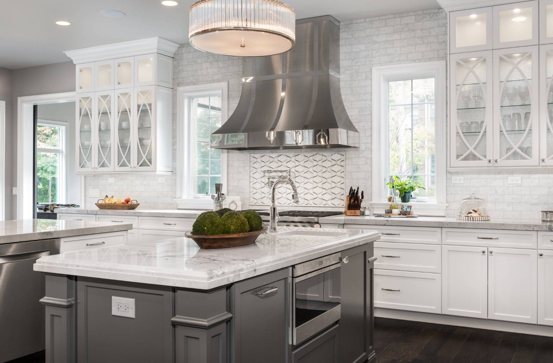A kitchen with white cabinets , stainless steel appliances , and a large island.