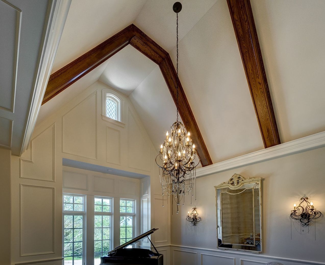 A room with a piano and a chandelier hanging from the ceiling