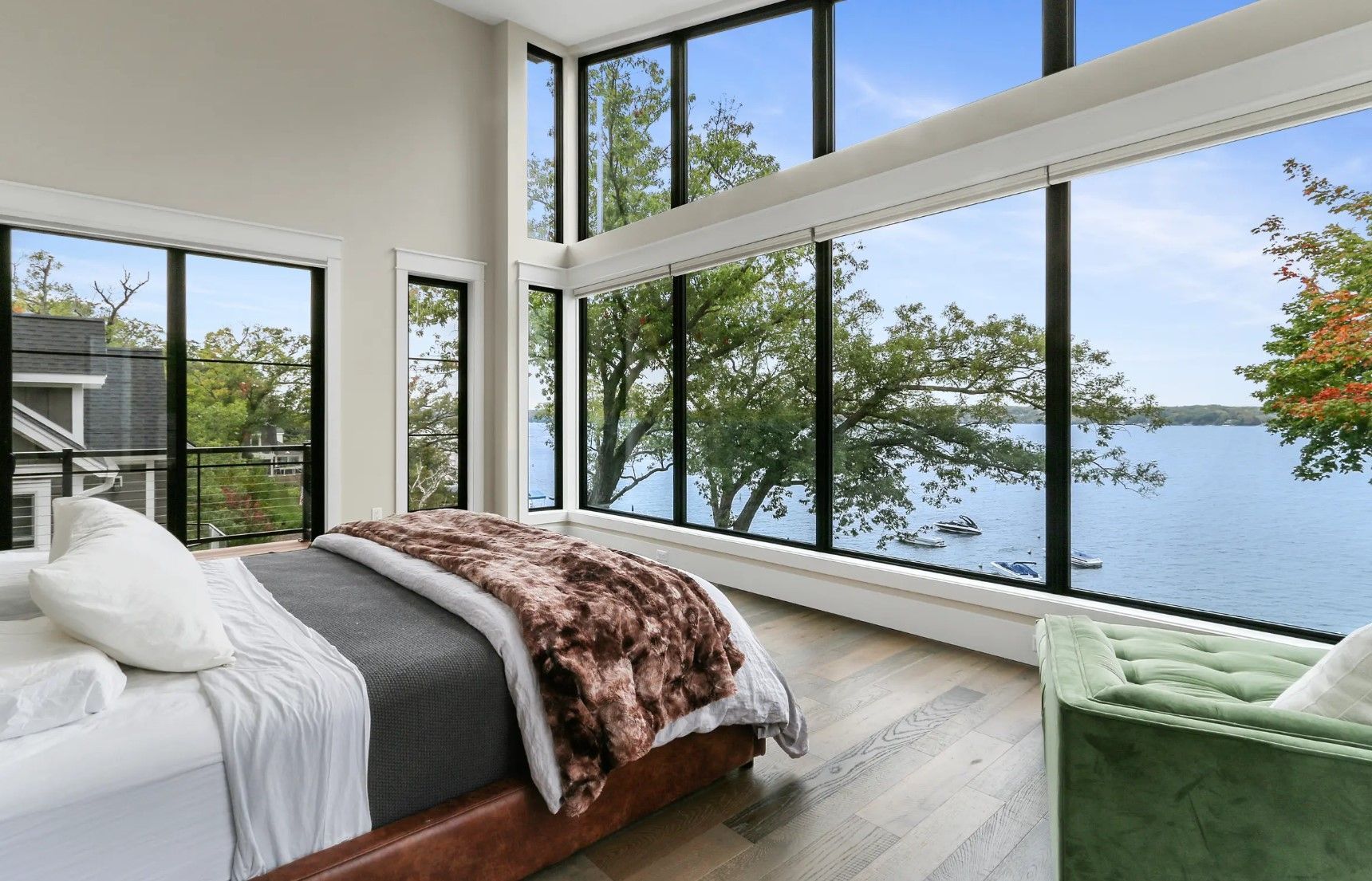 A bedroom with a large bed and lots of windows overlooking a lake.