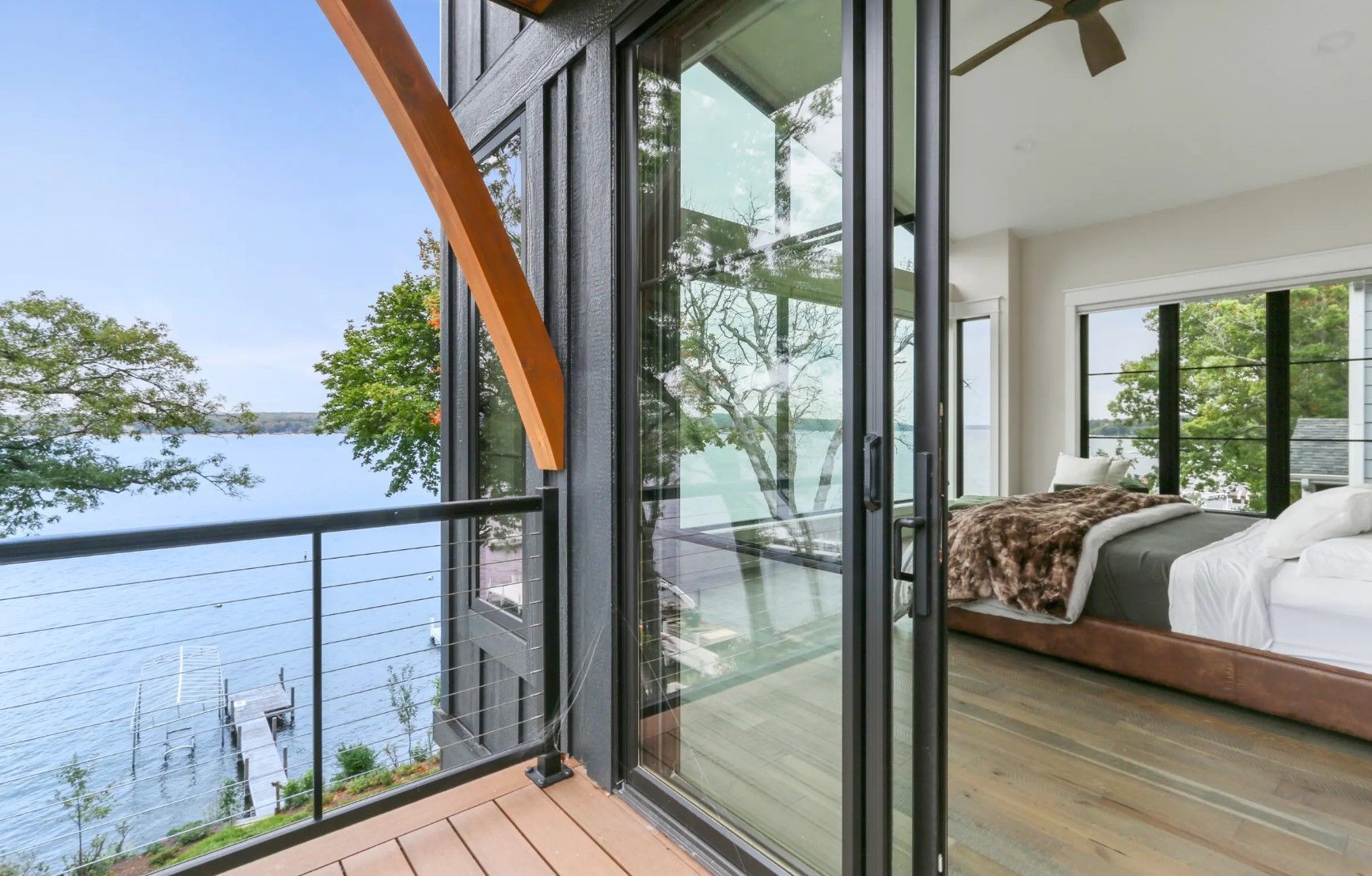 A bedroom with a balcony overlooking a lake.