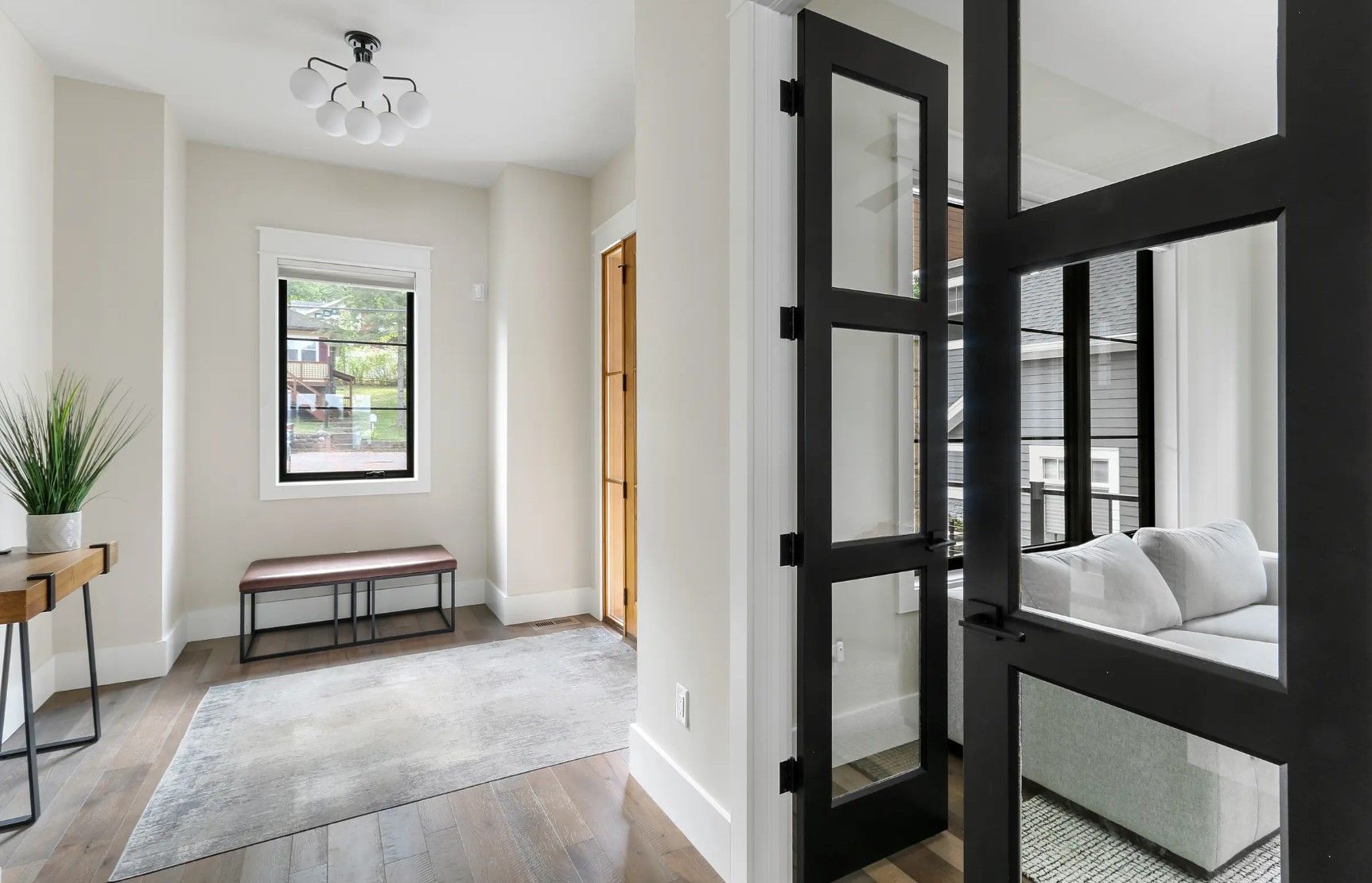 A living room with a couch , table , window and black doors.
