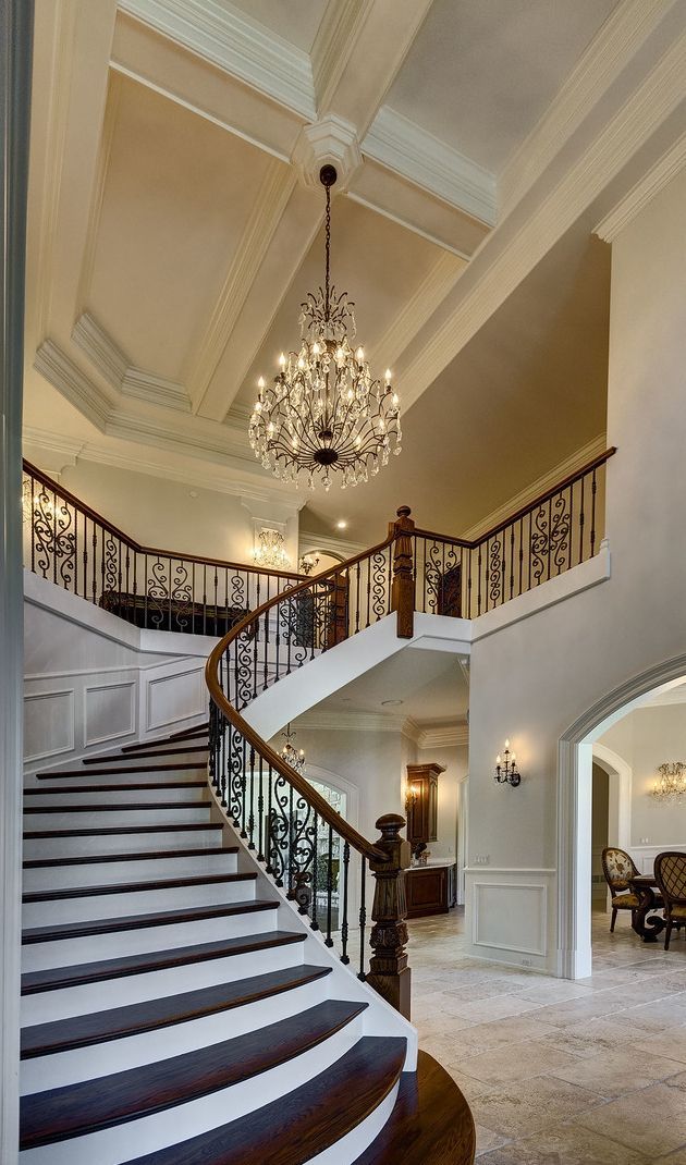 A large staircase in a house with a chandelier hanging from the ceiling.