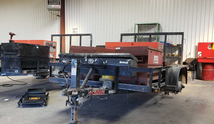 A trailer is sitting in a garage next to a machine.