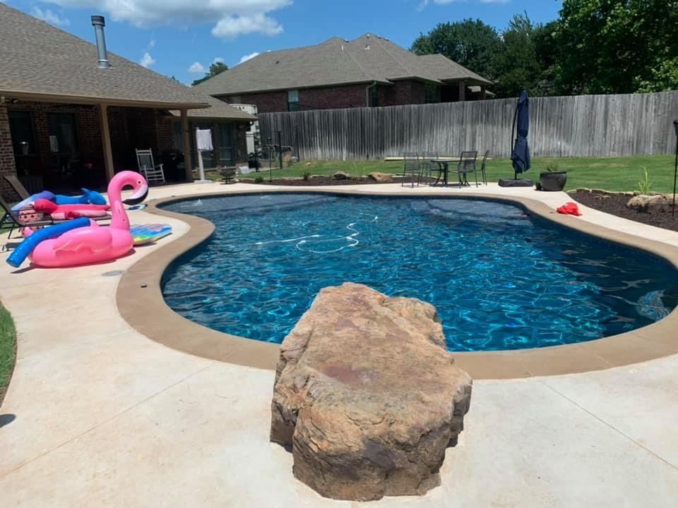 A large swimming pool with a rock in the middle of it