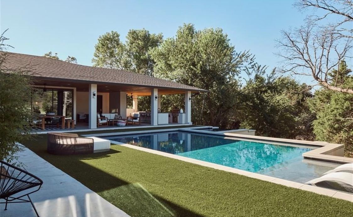 There is a large swimming pool in the backyard of a house.