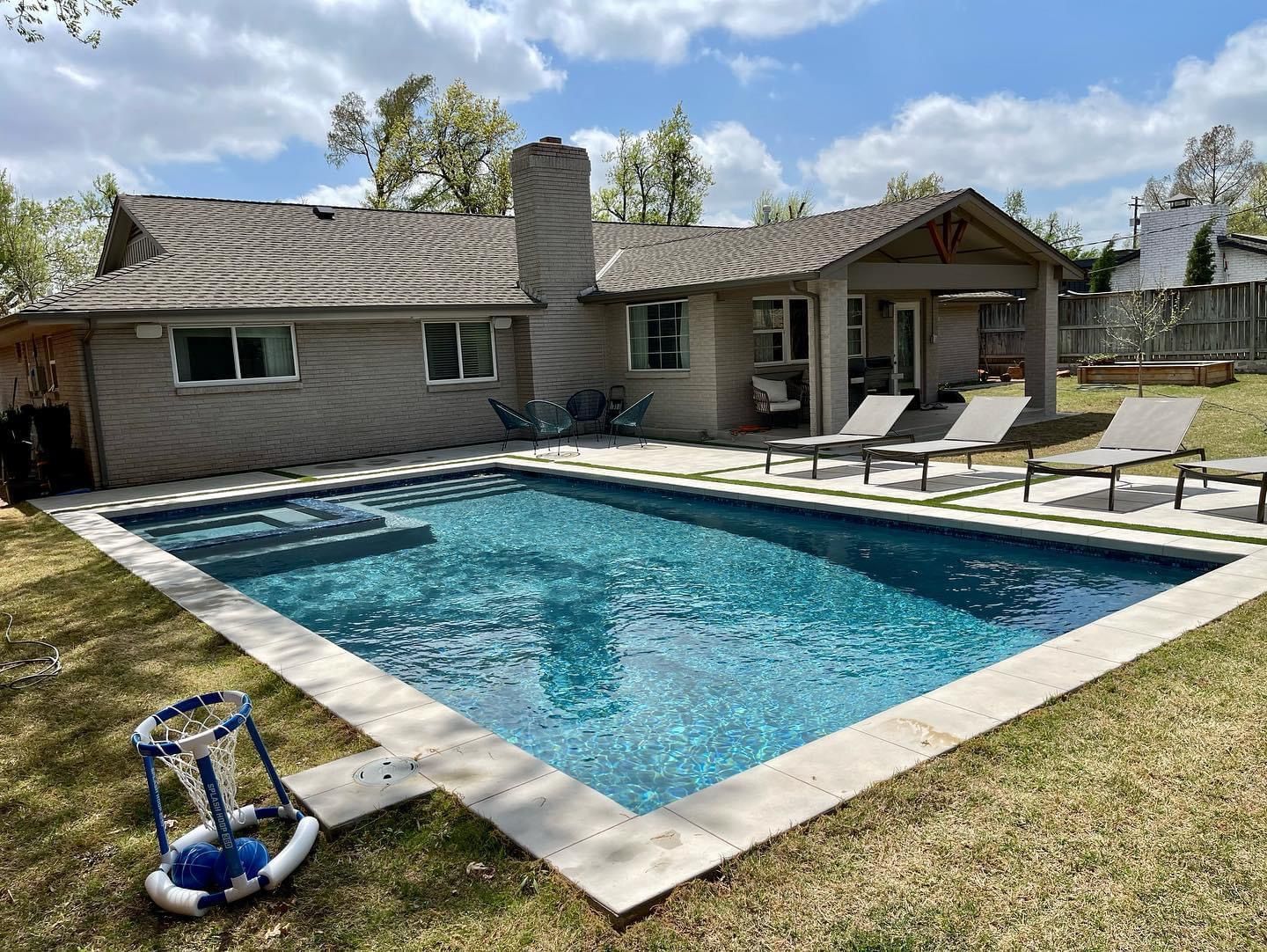 A large swimming pool is in the backyard of a house.