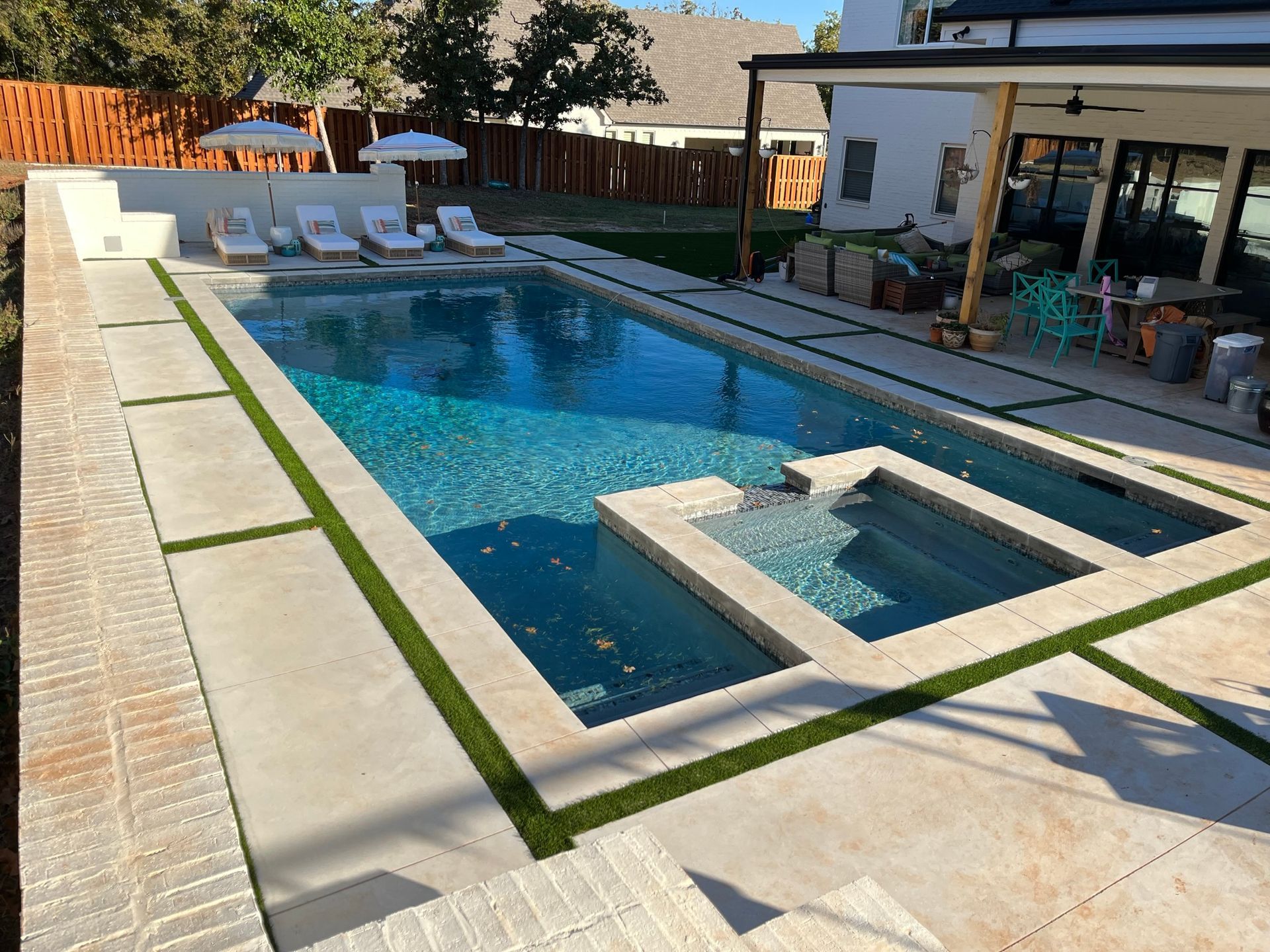 A large swimming pool with a hot tub in the backyard of a house.