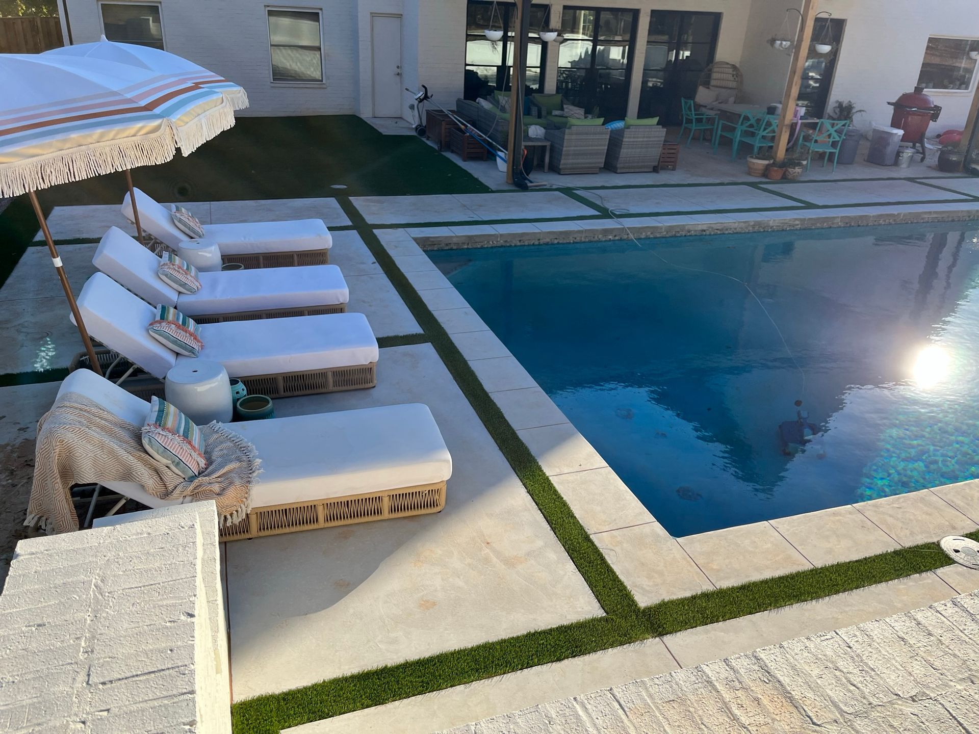 A row of lounge chairs are lined up next to a large swimming pool.