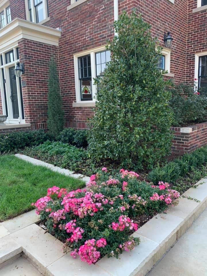 A brick house with pink flowers in front of it