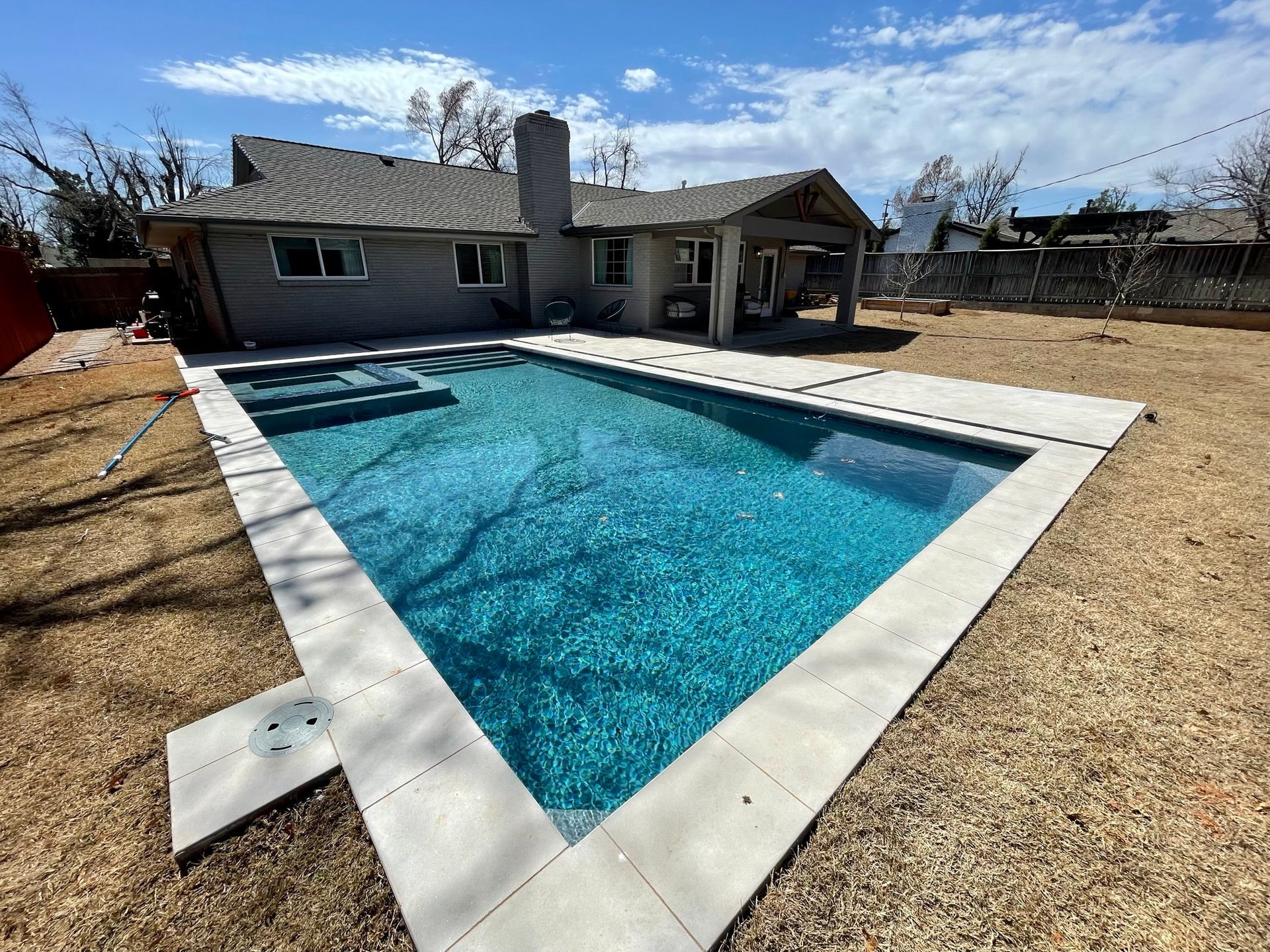 A large swimming pool is in the backyard of a house.
