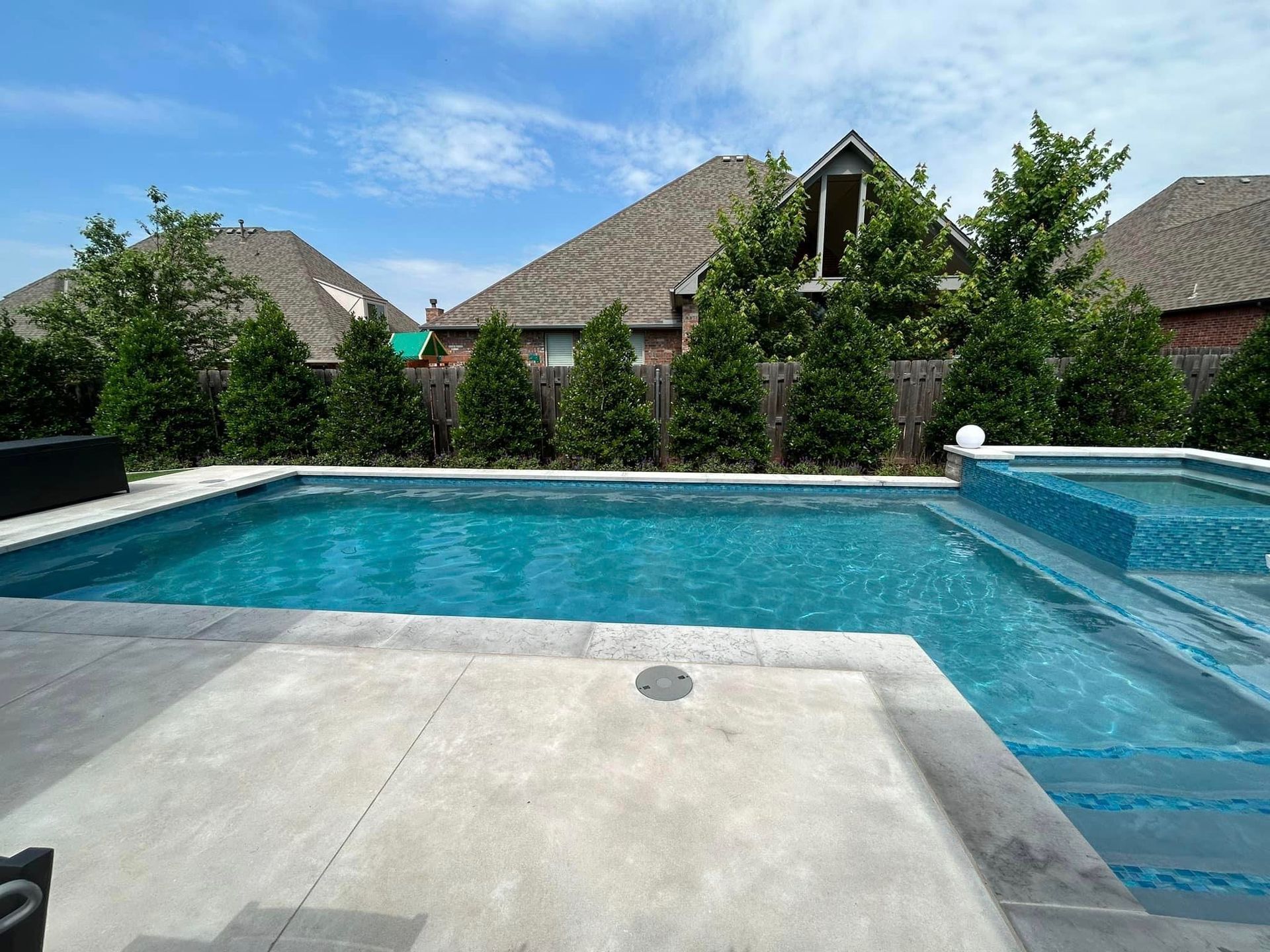 There is a large swimming pool in the backyard of a house.