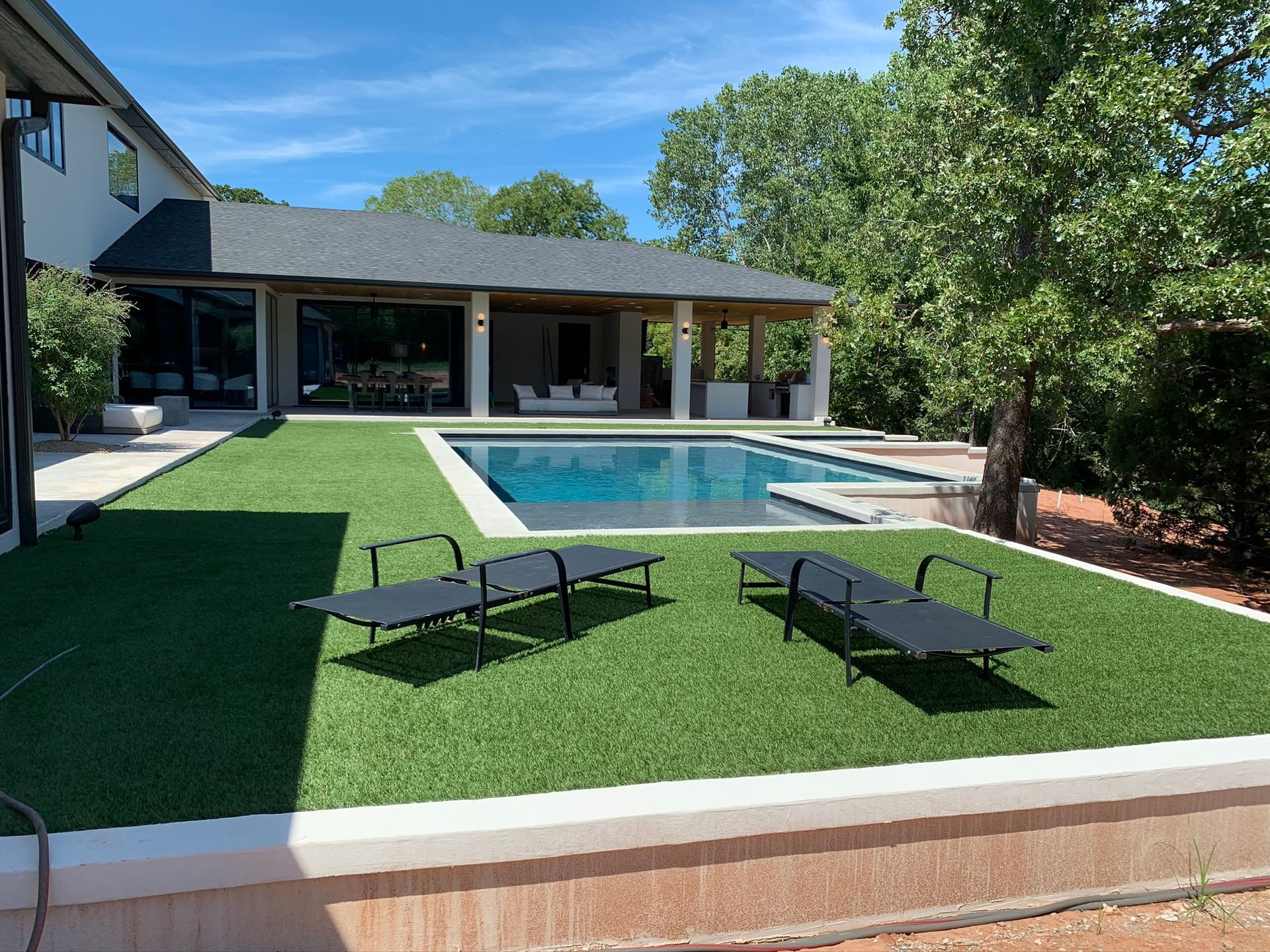 A large house with a swimming pool and lawn chairs in front of it.