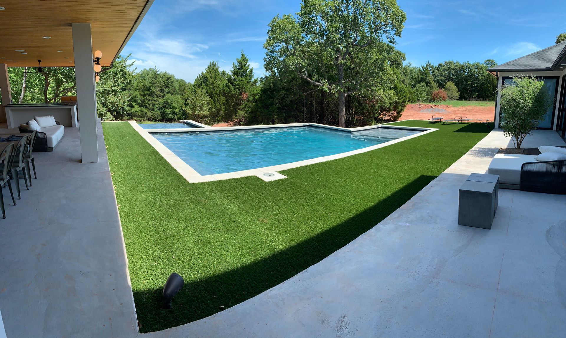 A large swimming pool is in the middle of a lush green lawn.