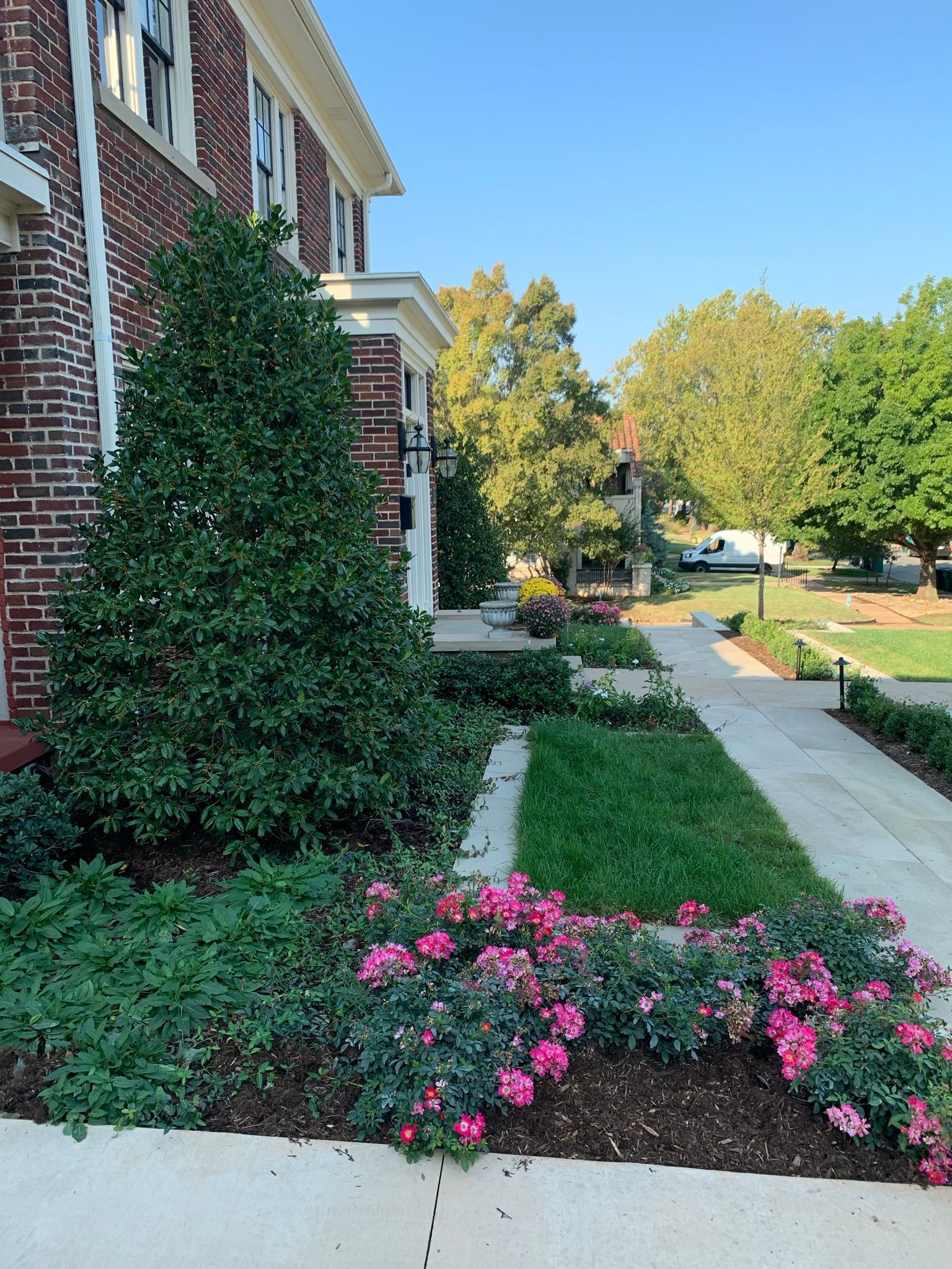 A brick building with a sidewalk and flowers in front of it.
