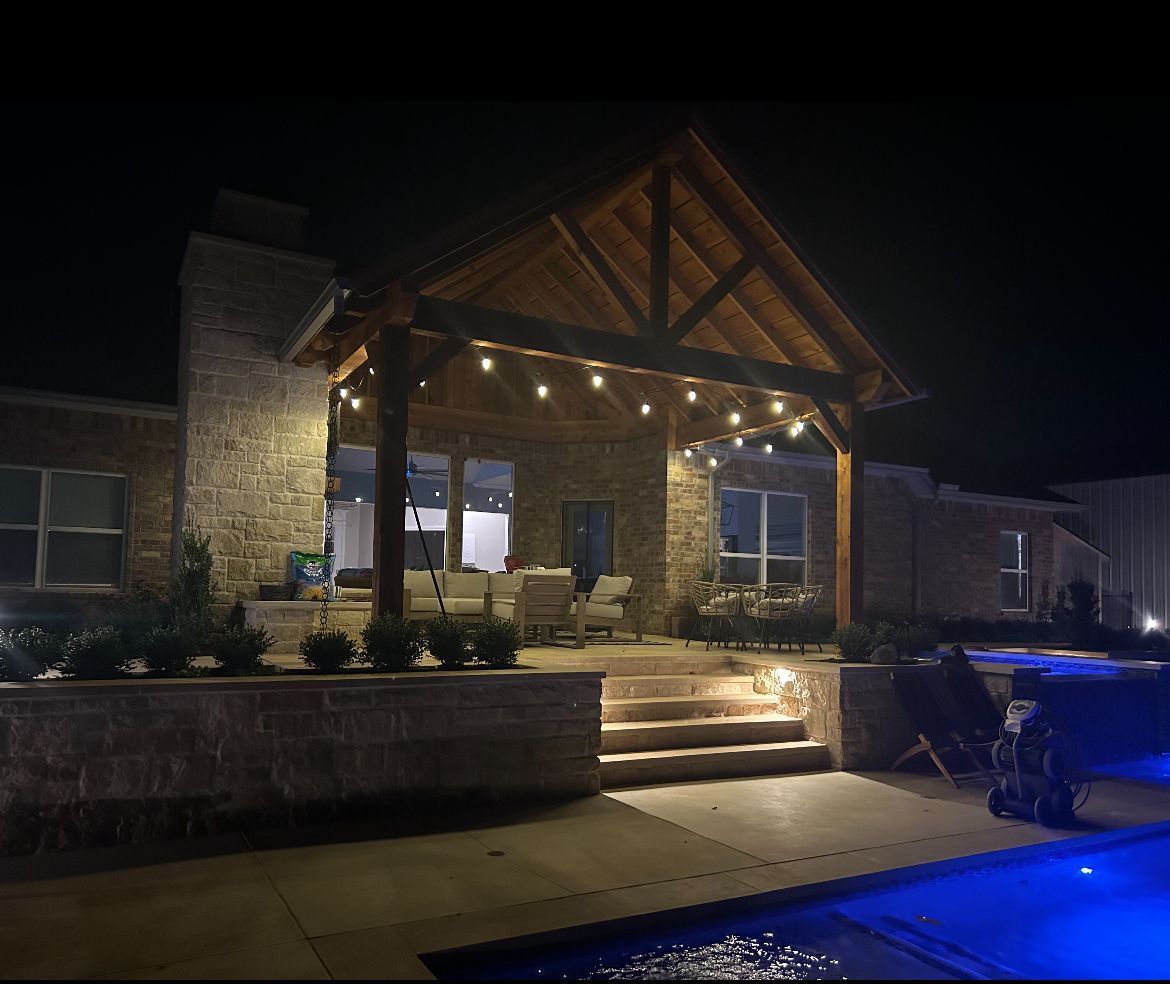 A house with a covered porch and a pool at night