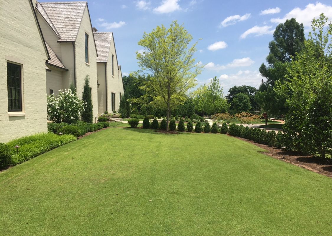 A large white house with a lush green lawn in front of it.