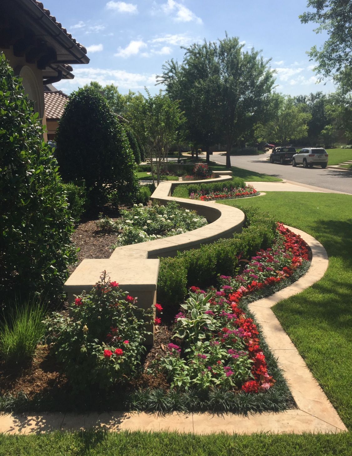 A garden with flowers and a walkway in front of a house.
