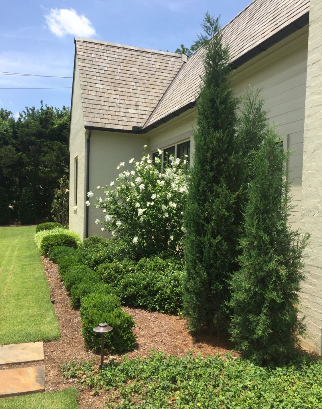 A white brick house with a roof that is covered in shingles