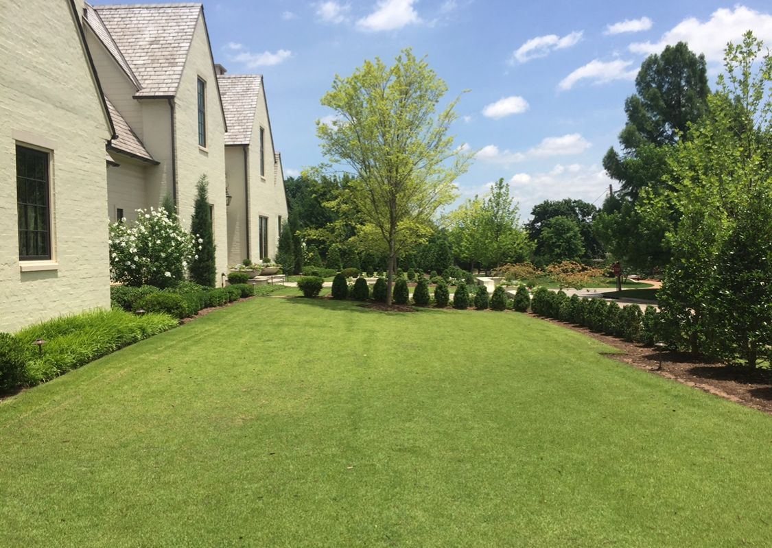 A large white house with a lush green lawn in front of it.