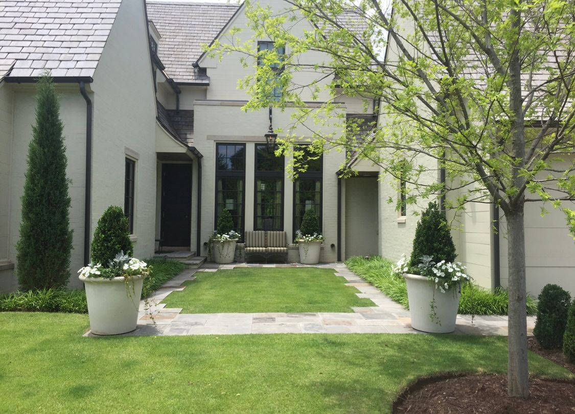 A large white house with a lush green lawn and trees in front of it.