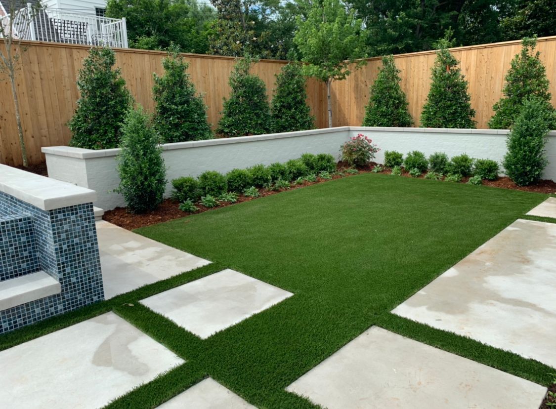 A backyard with a fence and a lush green lawn.