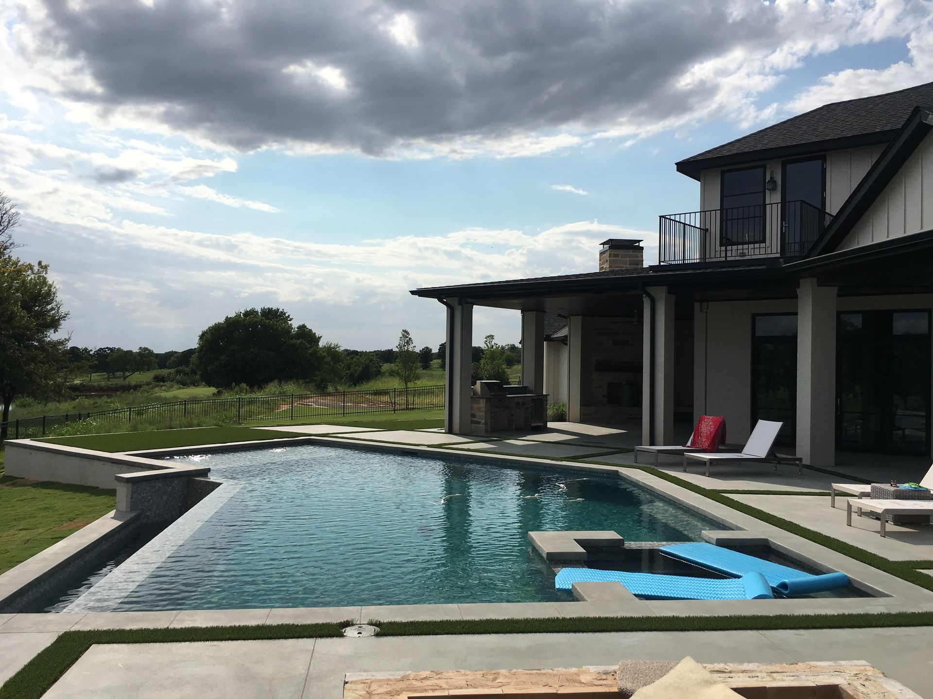 A large swimming pool is in the backyard of a house.