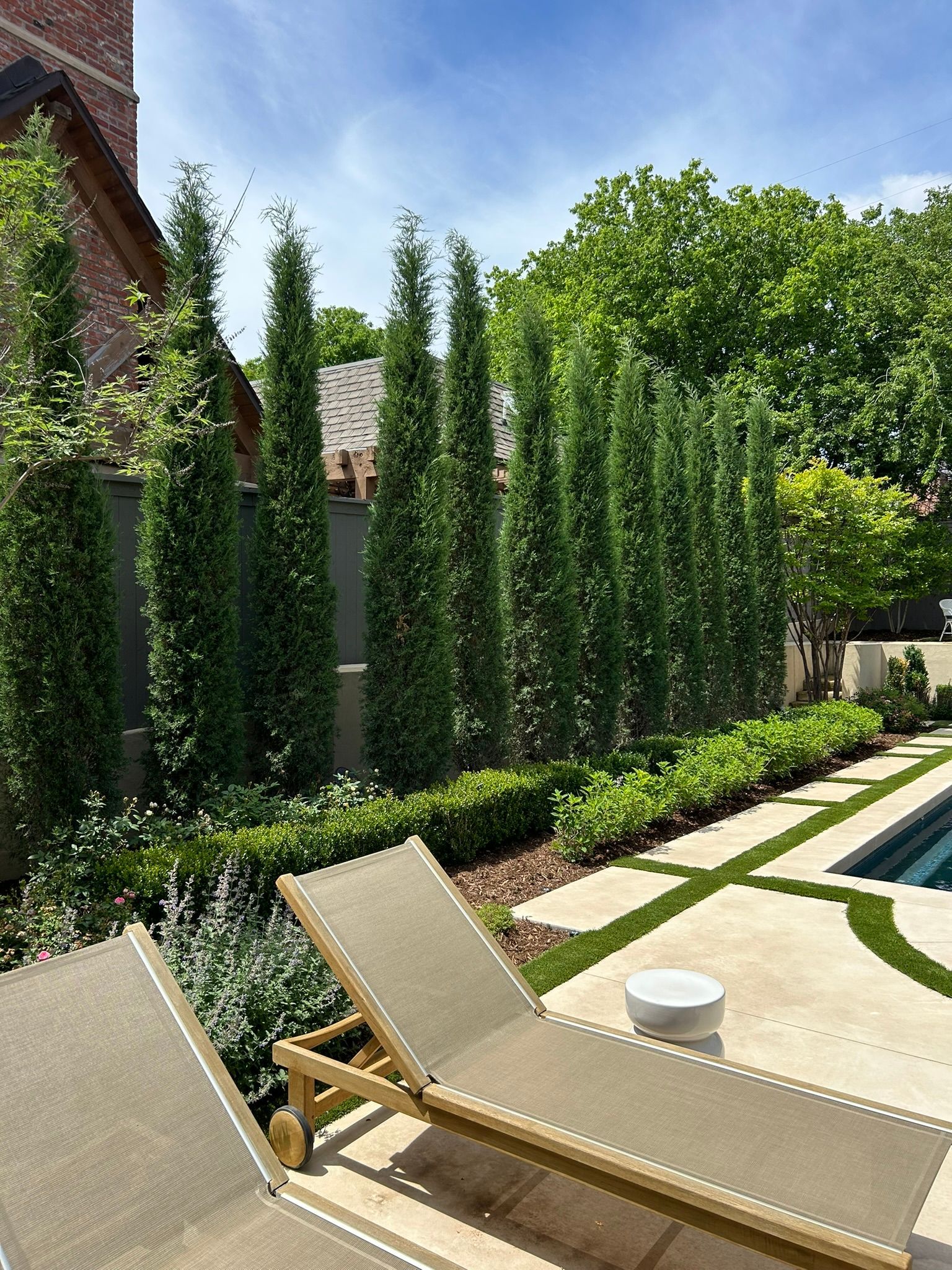 Two lounge chairs are sitting next to a swimming pool in a backyard.