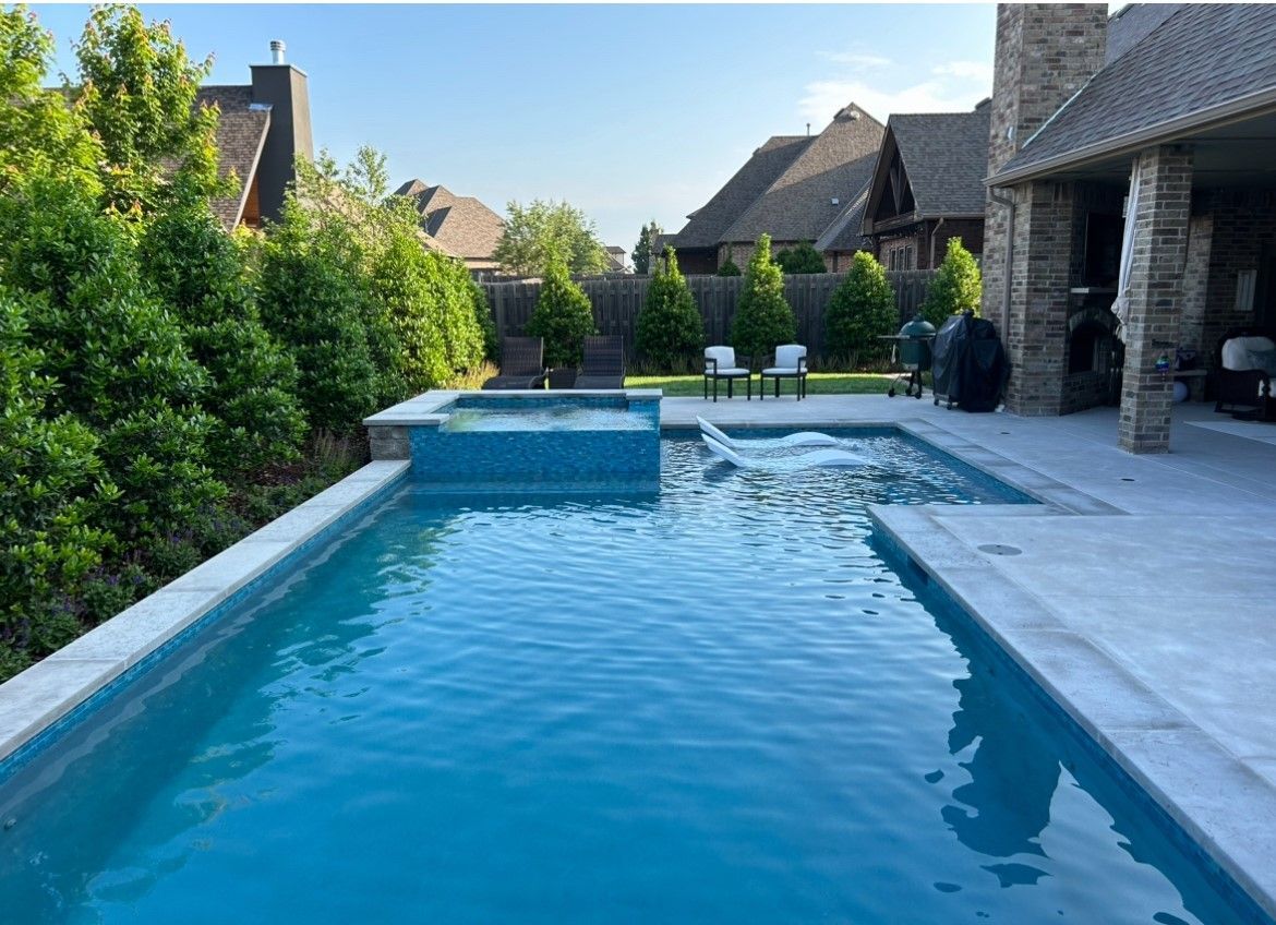 A large swimming pool is in the backyard of a house.