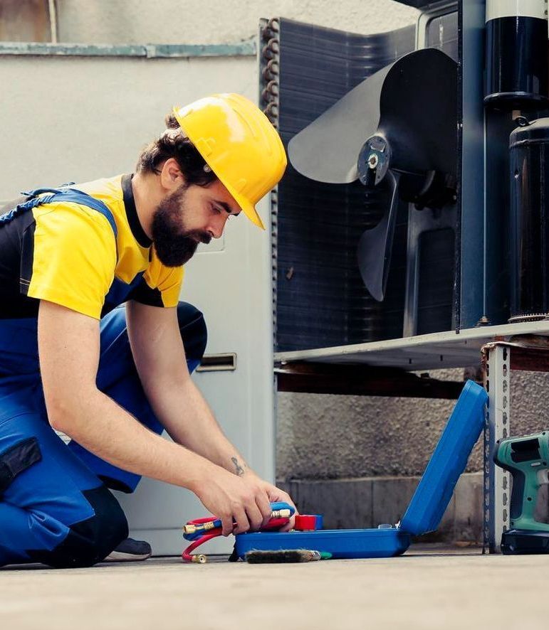 A man wearing a hard hat is working on a machine
