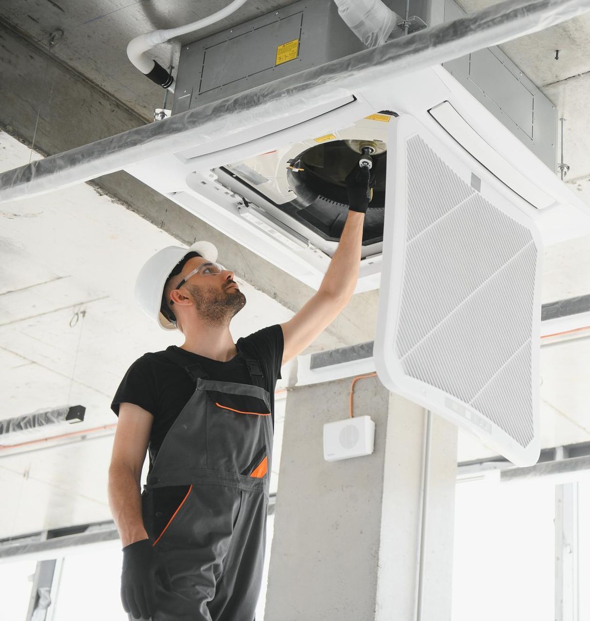 A man is working on a ceiling fan in a building.