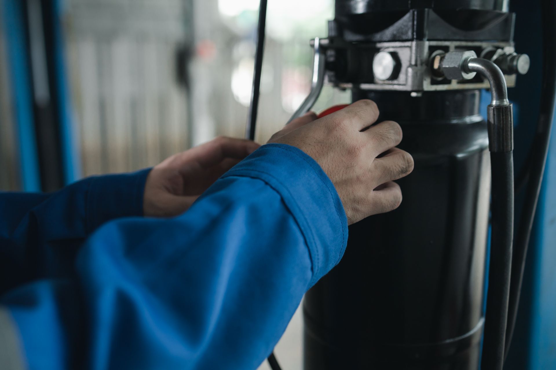 A man in a blue jacket is working on a machine. 