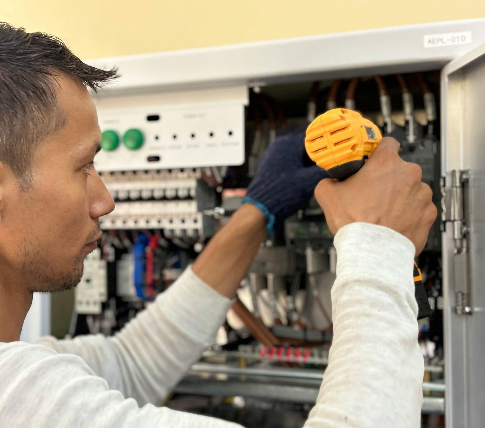 A man wearing a hard hat is working on an air conditioner. 