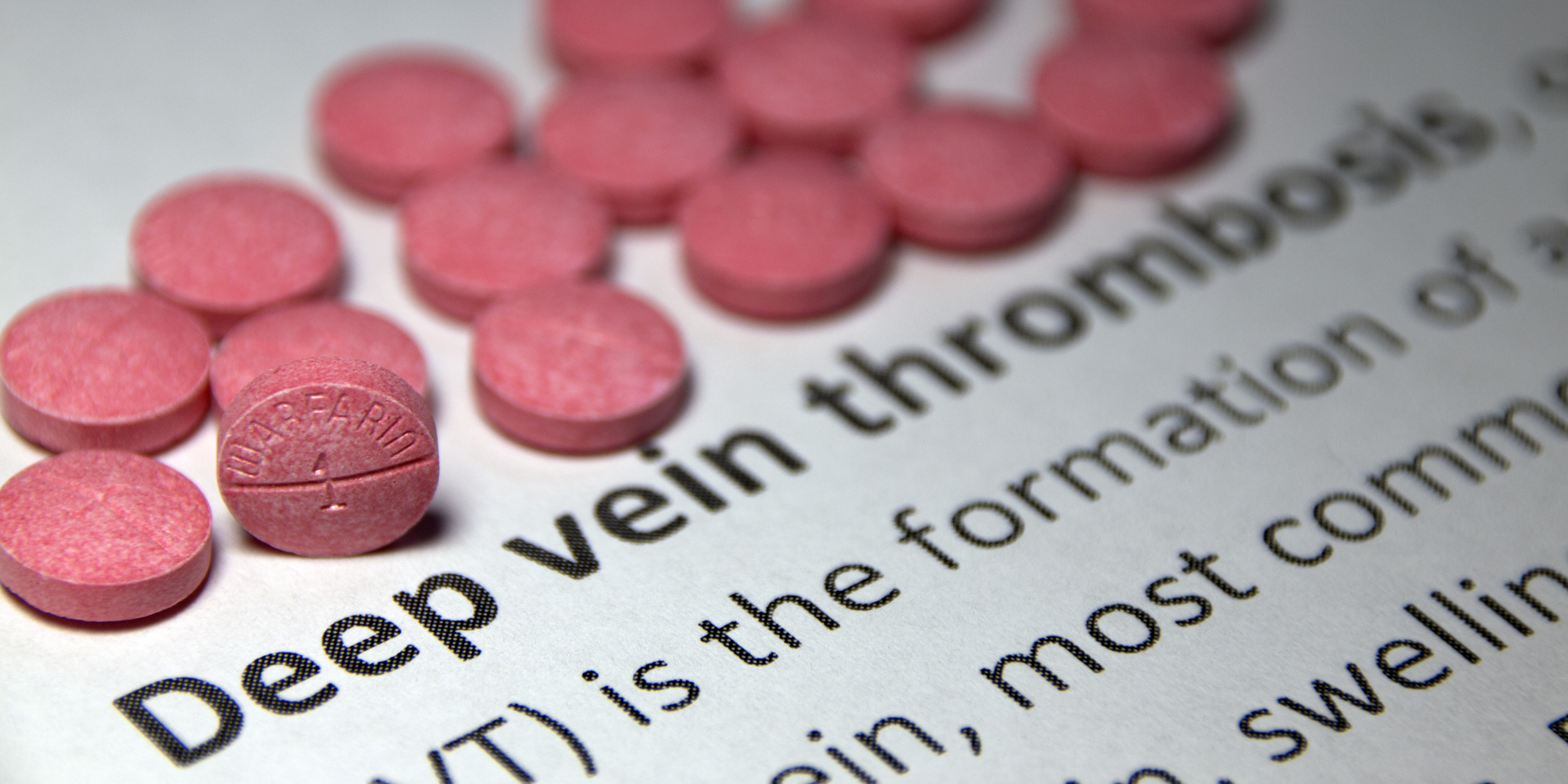 A bunch of pink pills on top of a page that says deep vein thrombosis