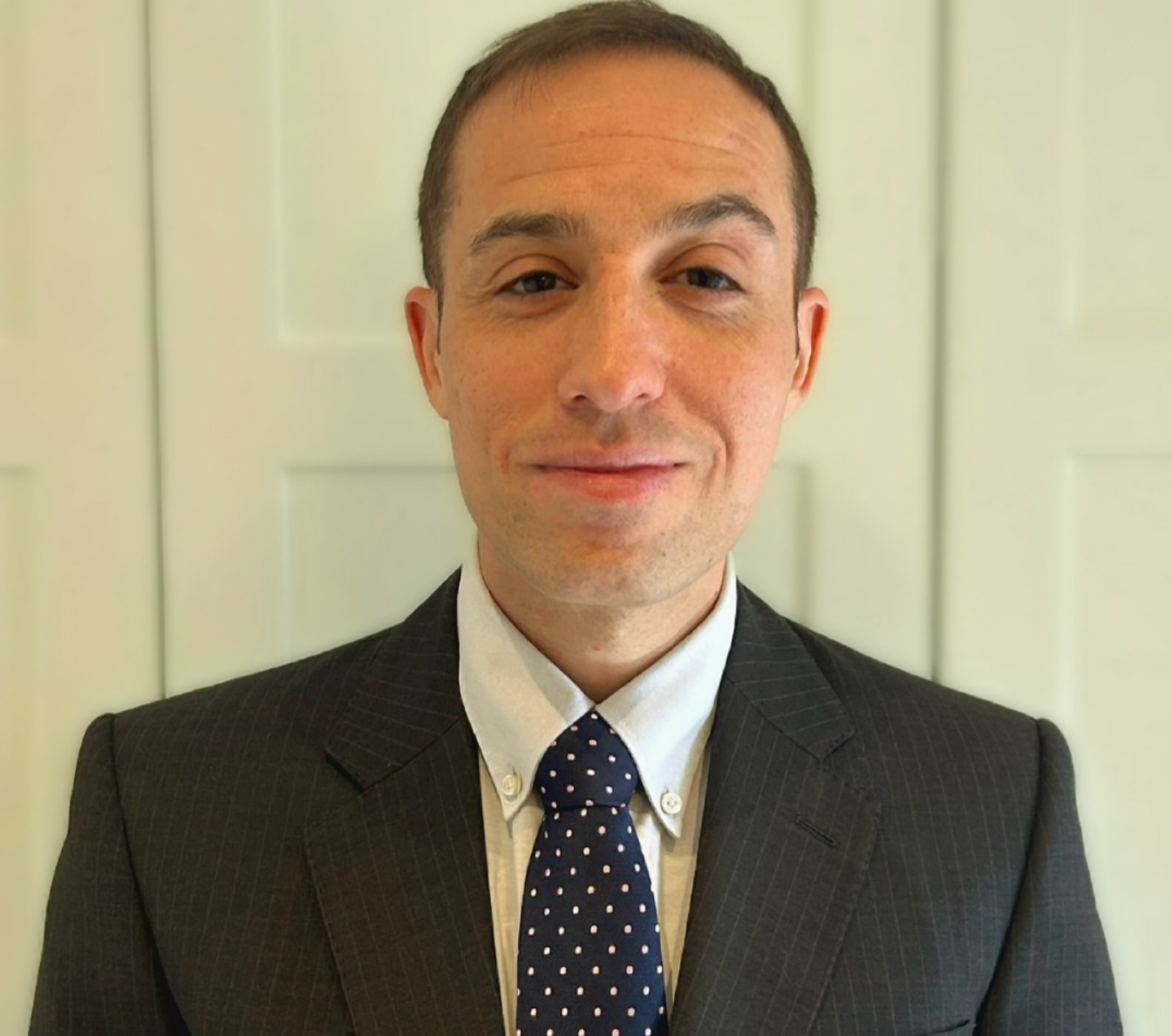 A man in a suit and tie is smiling for the camera