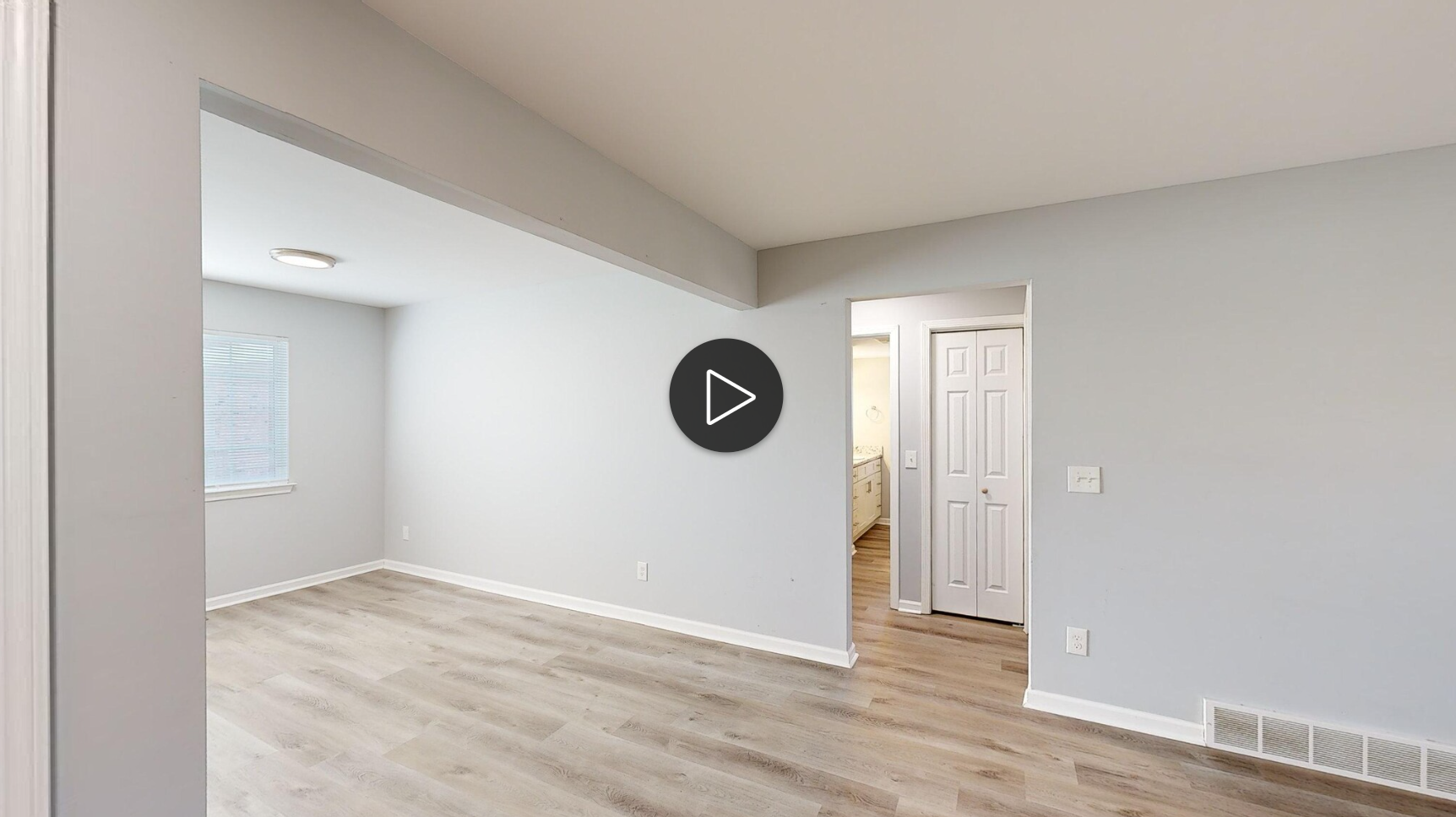 A living room with hardwood floors and a play button on the wall.