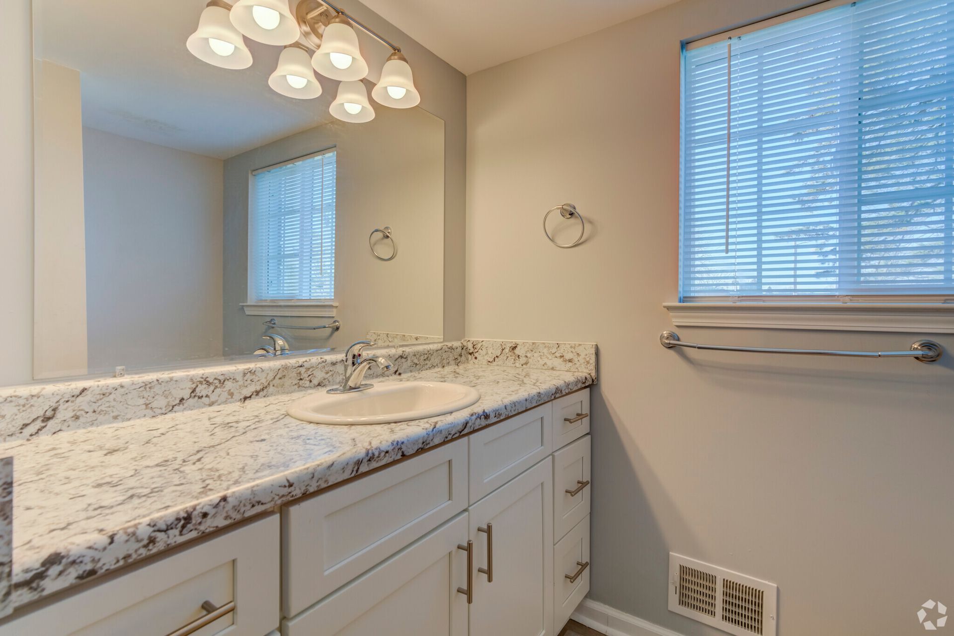 A bathroom with a sink , mirror and window.