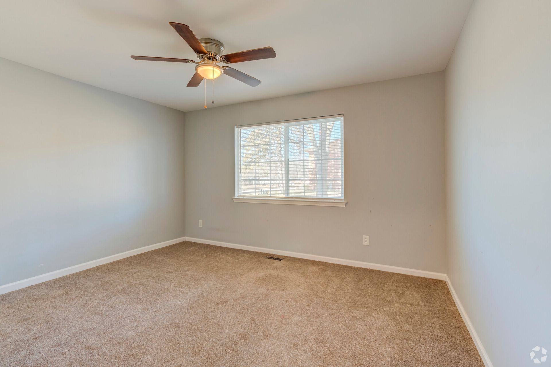 An empty bedroom with a ceiling fan and a window.