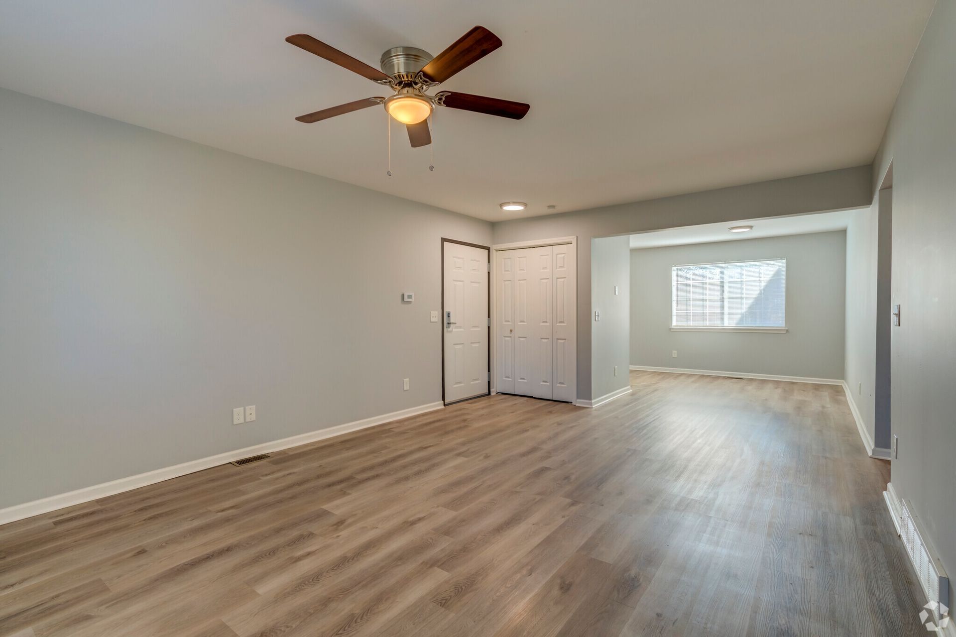 An empty living room with hardwood floors and a ceiling fan.