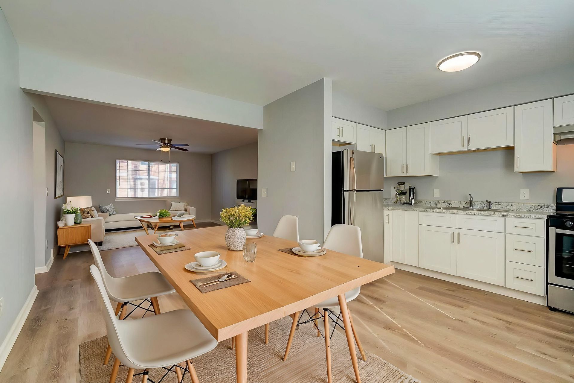A kitchen and living room in an apartment with hardwood floors and stainless steel appliances.