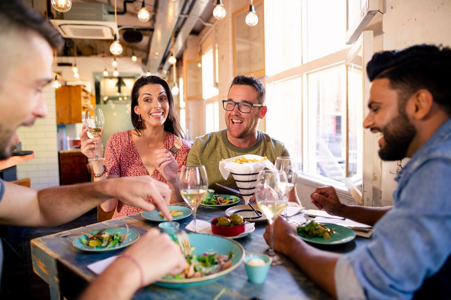 A group of people are sitting at a table in a restaurant eating food.