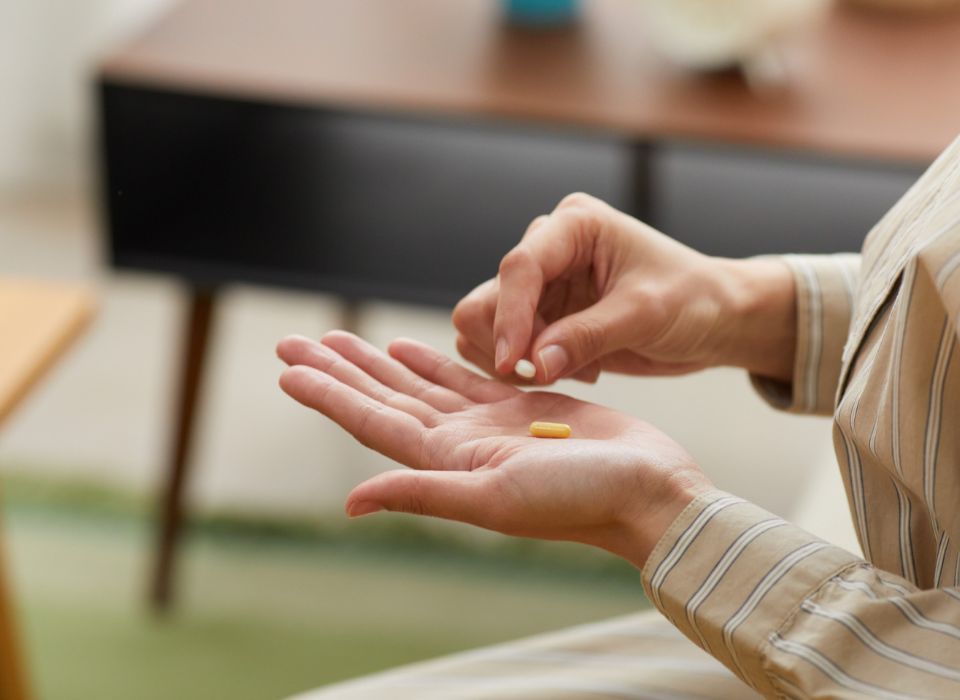 Woman smiles, applying product to clear aligner. Gray background, white shirt.