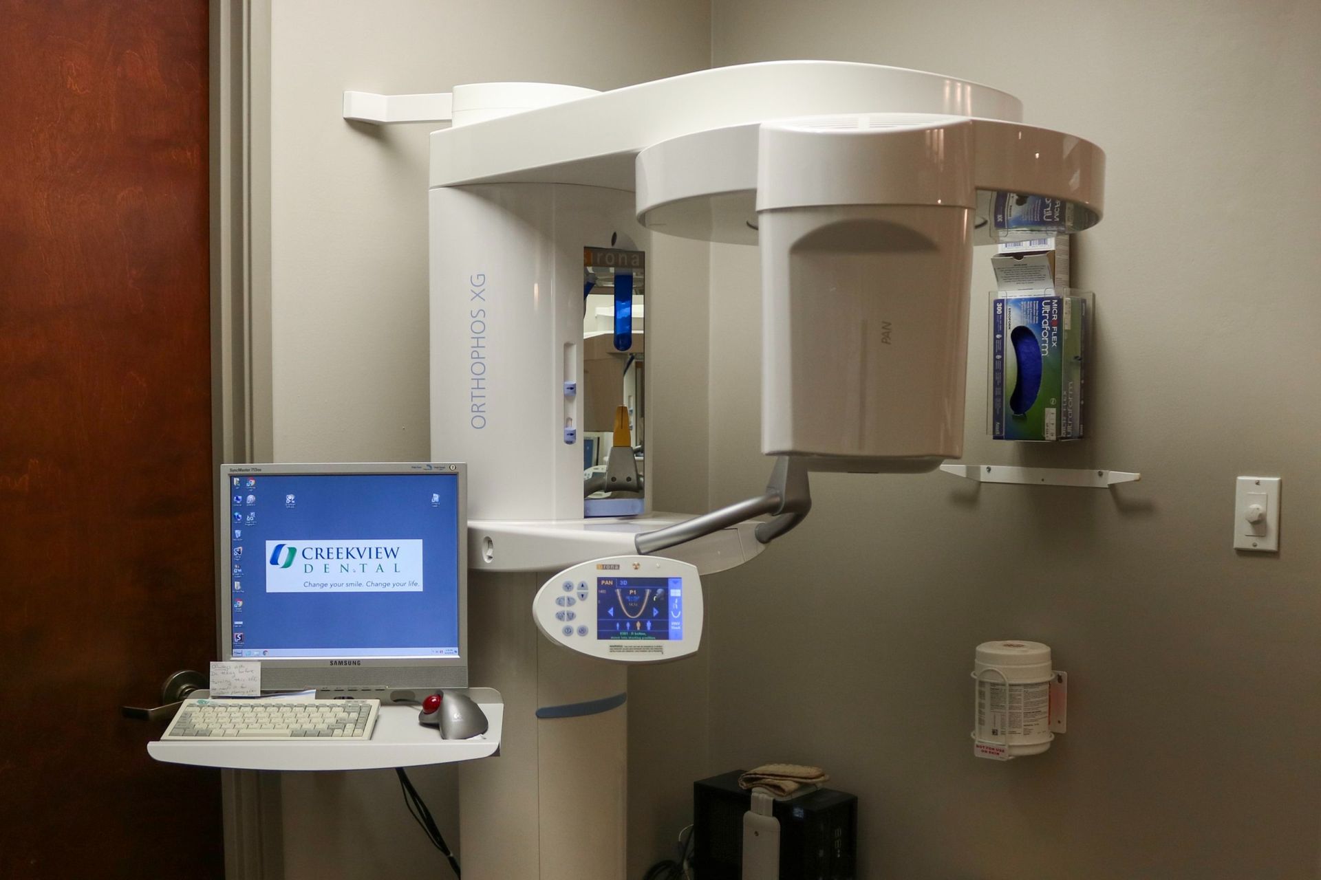Dental panoramic X-ray machine in a medical office next to a computer.