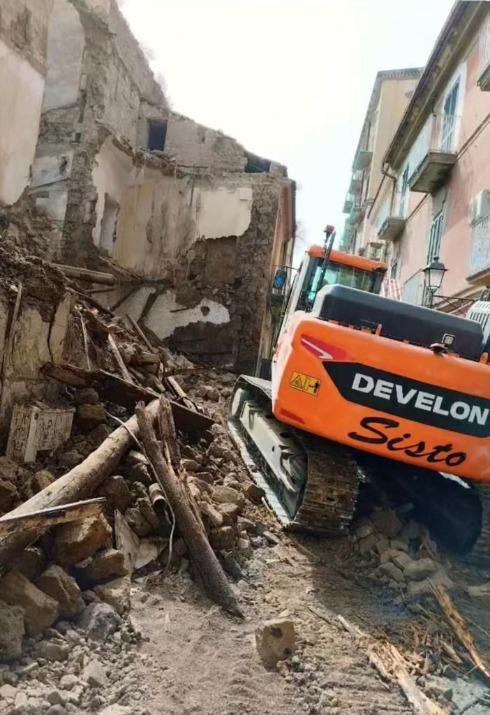 Una ruspa sta demolendo un edificio in una città.