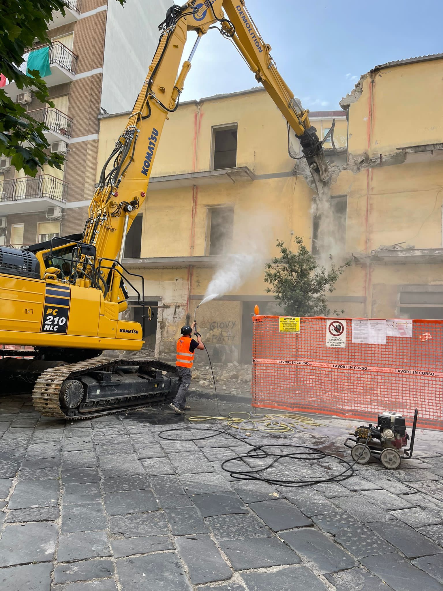 Un grande escavatore giallo sta demolendo un edificio.
