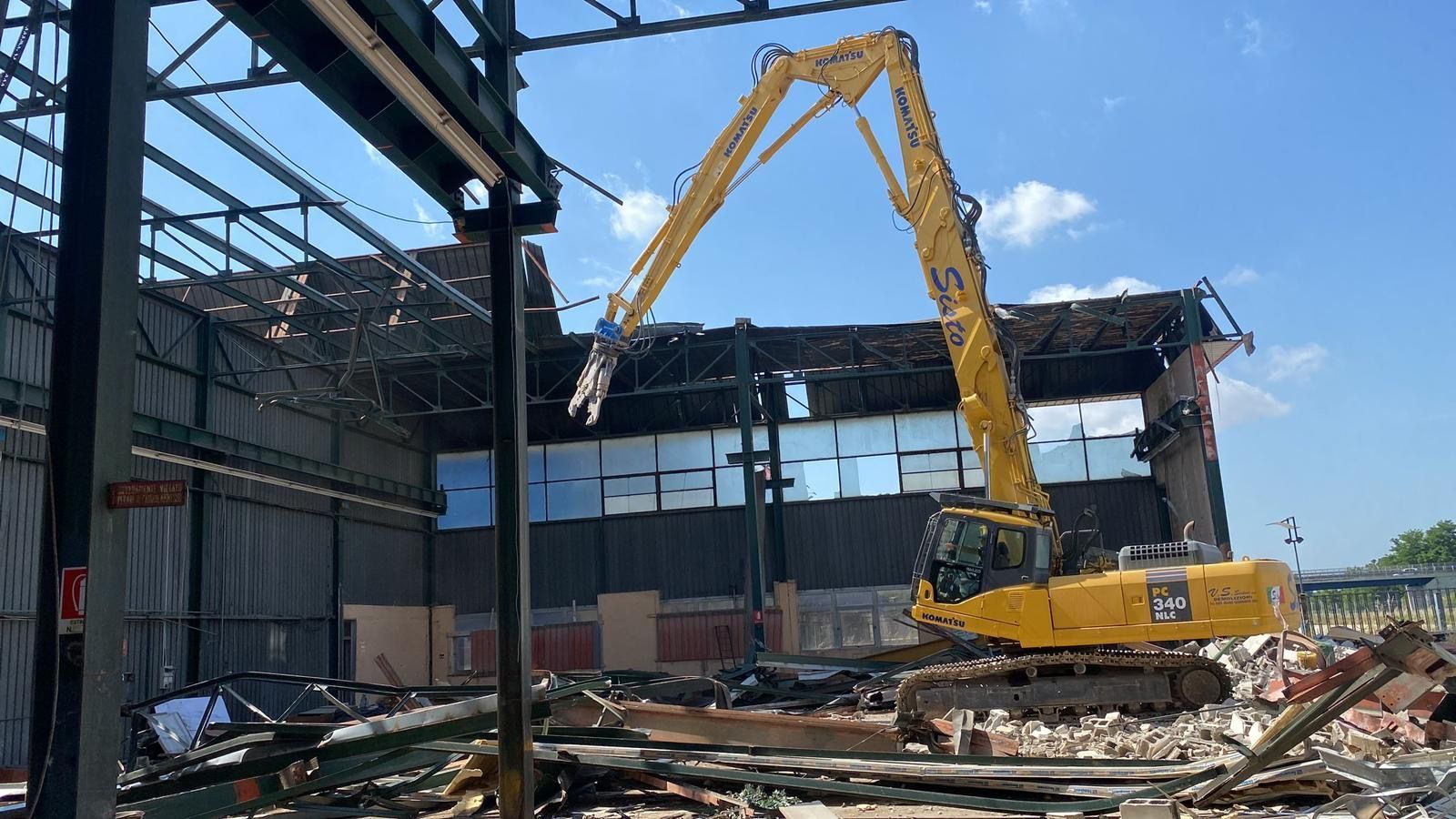 Un grande escavatore giallo sta demolendo un edificio.