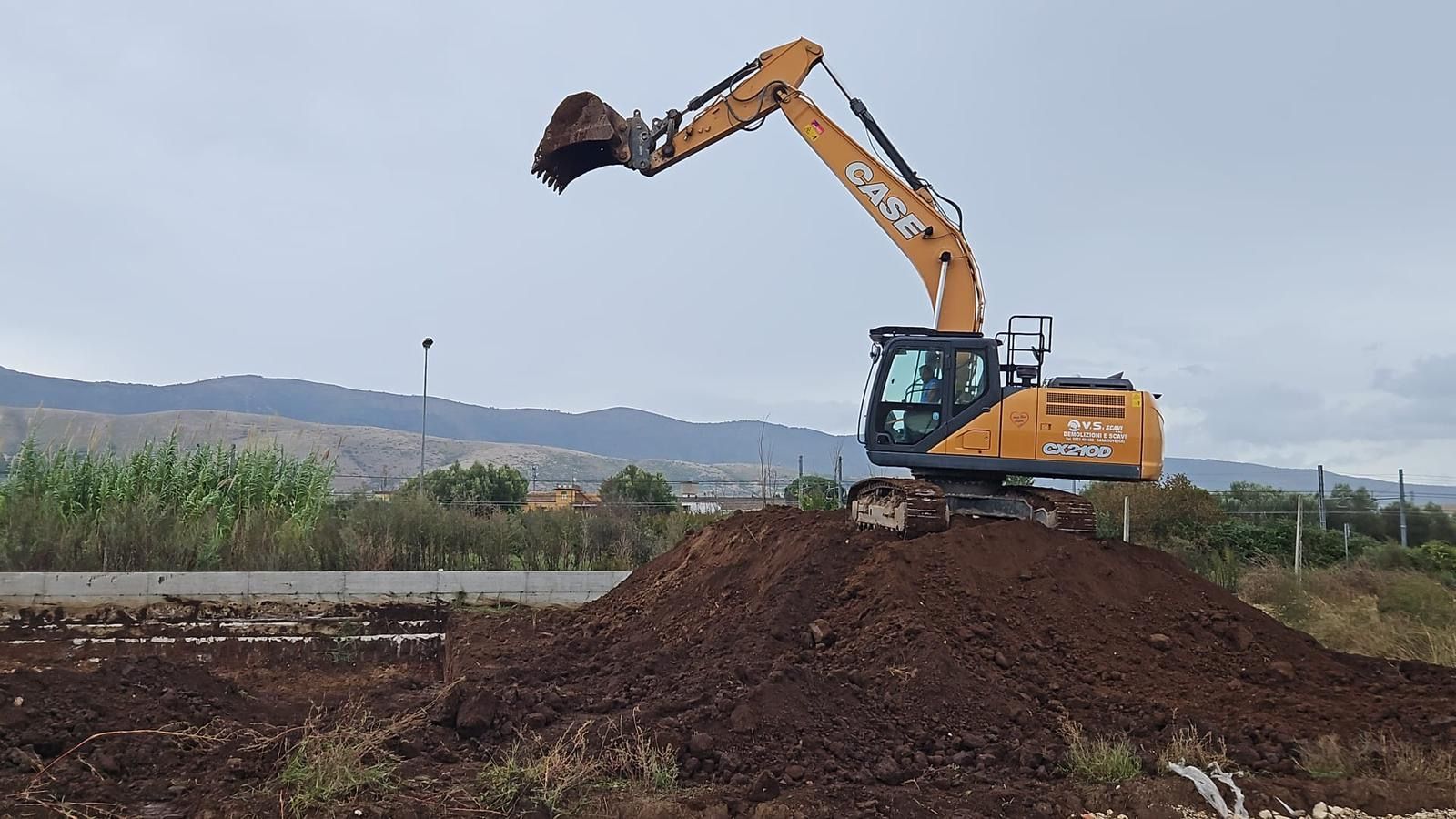 Un escavatore sta scavando un mucchio di terra in un campo.